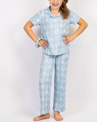 Girl wearing light blue patterned winter holiday pajama set with short sleeve top and matching pants.