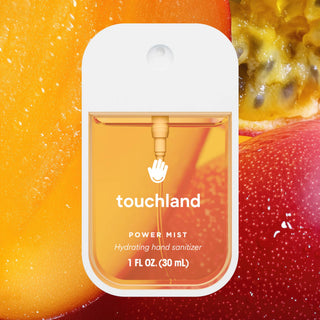 Touchland Power Mist hydrating hand sanitizer in white dispenser against colorful fruit background