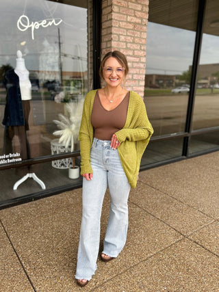 Woman wearing an oversized knit cardigan paired with patterned wide-leg jeans outside a boutique.