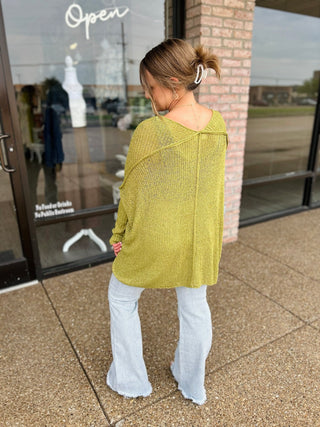 Woman wearing a lightweight open-knit oversized cardigan with long sleeves, shown from behind.