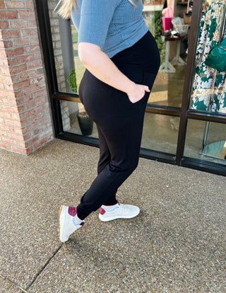 Pregnant woman wearing black knit jogger pants and blue sweater, showing maternity fit and comfort.