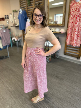 Woman wearing beige ribbed top and floral mauve midi skirt in clothing boutique store
