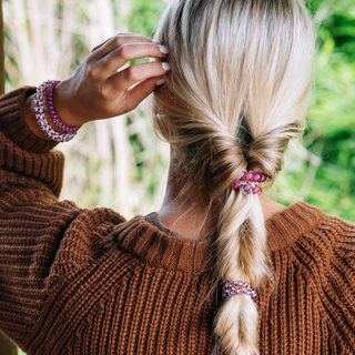 Person wearing TELETIES Small Hair Ties in a braided ponytail with matching bracelet, brown sweater.