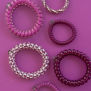 TELETIES spiral hair ties in solid and patterned styles arranged on a purple background.