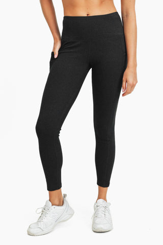 Woman wearing dark gray high-waisted ribbed leggings with side pocket and white sneakers
