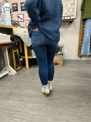 Person wearing dark wash skinny jeans and navy sweater walking in retail store