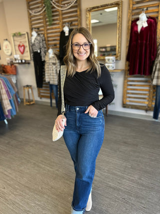 Woman wearing black long-sleeve bodysuit with jeans in clothing boutique store setting