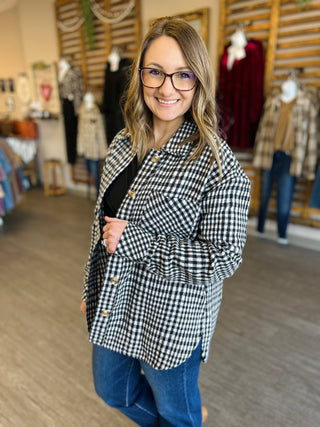 Woman wearing black and white checkered plaid button-up shacket over dark top in clothing store