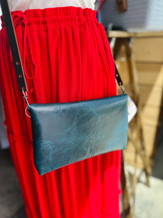 Woman wearing red skirt carrying navy blue leather envelope crossbody bag with black strap