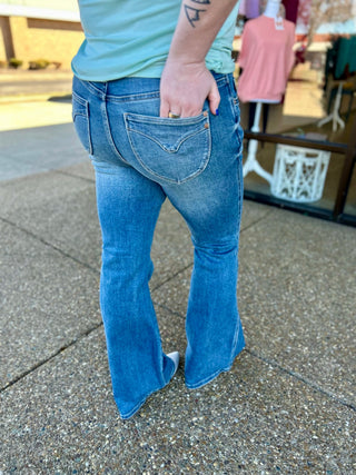 Woman wearing Judy Blue midrise tummy control vintage flare jeans with hand in back pocket.