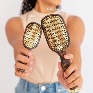 Woman holding two TELETIES vented hair brushes with gold bristle plates and tortoise shell handles.