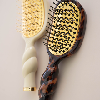 Two TELETIES Mini Vented Brushes with twisted handles, gold cushioned bases, and ball-tipped bristles.