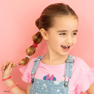 Young girl wearing denim overalls and pink Minnie Mouse shirt with colorful hair ties in braided ponytail.