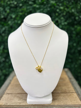 Gold charm necklace with heart and sun pendants displayed on white jewelry bust stand.