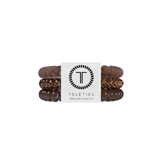 Three spiral coil hair ties in warm brown tones displayed on a TELETIES branded card.