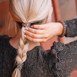 Person wearing TELETIES spiral hair ties in a braided hairstyle, with one on wrist as bracelet.
