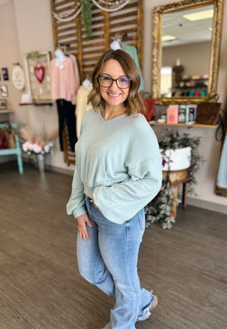 Woman wearing relaxed pullover sweater and jeans in boutique clothing store setting