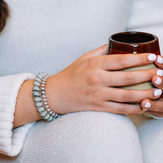 Hand wearing TELETIES hair ties as bracelets while holding a warm ceramic mug.