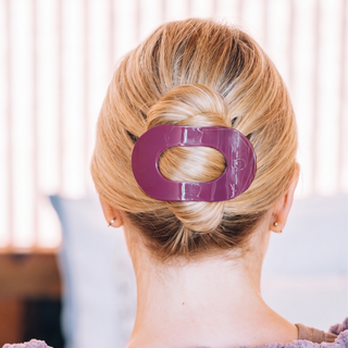 Person wearing a large flat round hair clip securing an elegant twisted updo hairstyle.