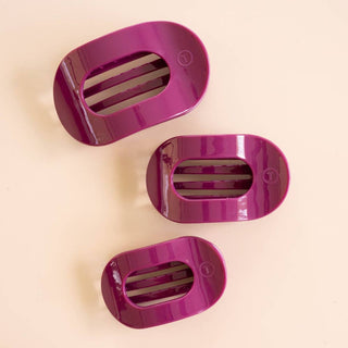 Three glossy oval-shaped flat round hair clips in graduating sizes on a neutral background.