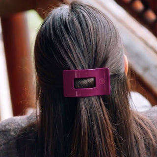 A hair clip securing long dark hair, shown from behind on a model outdoors.