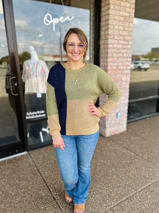 Woman wearing Blu Pepper colorblock knit sweater with jeans, posing outside boutique storefront.