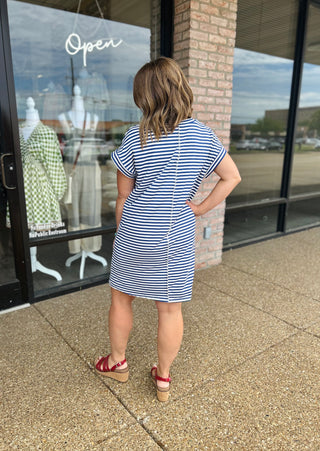 Woman modeling Haptics striped t-shirt dress with short sleeves, shown from behind, paired with wedge sandals.