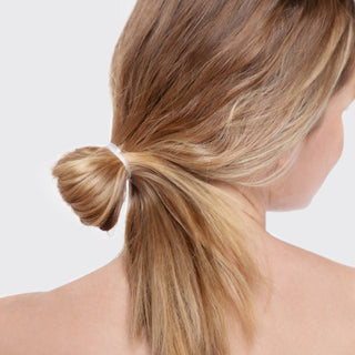 Woman with blonde hair in low ponytail secured with clear elastic hair tie