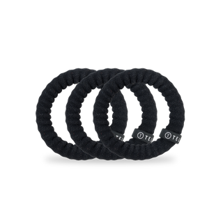Five black twisted nylon hair ties arranged in an overlapping row against white background