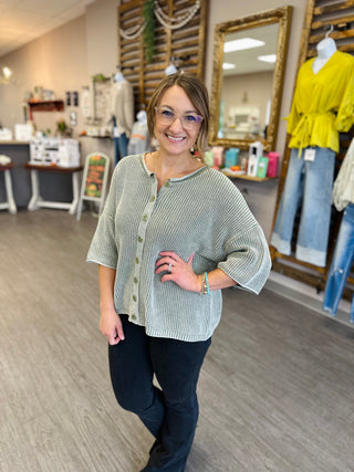 Woman smiling in a relaxed-fit ribbed knit button-front sweater top with three-quarter sleeves.