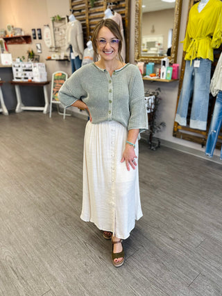 Woman wearing a cropped waffle-knit button-front sweater top paired with a white midi skirt.