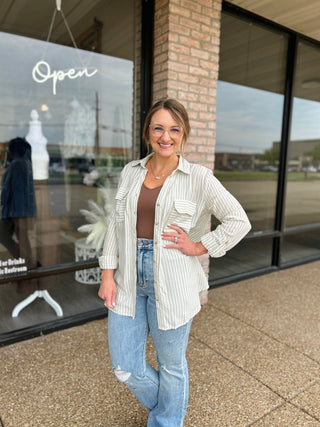 Woman wearing a striped button-down shirt jacket over a brown bodysuit with distressed jeans.