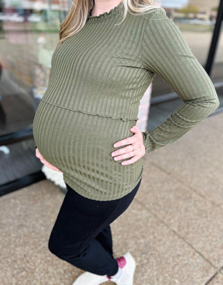 Pregnant woman wearing olive green ribbed knit maternity top with long sleeves and nursing-friendly design.