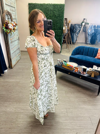 Woman wearing a floral midi dress with puff sleeves, sweetheart neckline, and flowy skirt.
