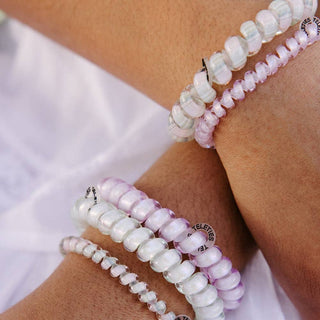 TELETIES hair ties in iridescent white and purple tones worn on wrist against white fabric background