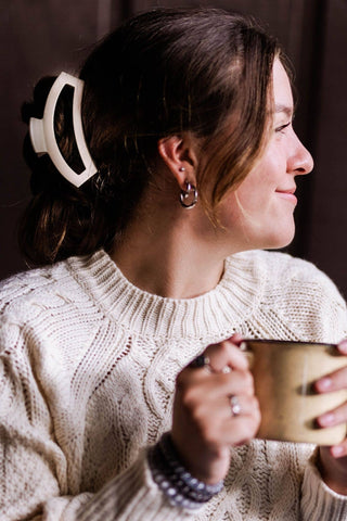 Woman wearing cream sweater with TELETIES open hair clip holding back brunette hair in updo style.
