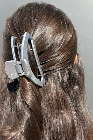 Silver metallic open hair clip securing brown hair in a twisted updo style.