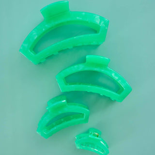 TELETIES open hair clip in bright green translucent plastic with curved spiral design on teal background