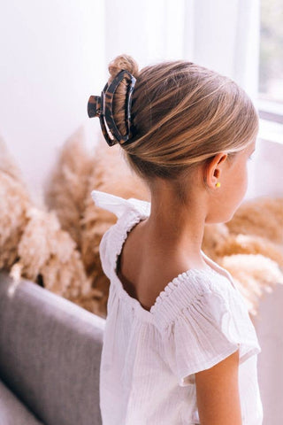 Woman wearing white top with hair secured in updo using tortoise shell hair clip