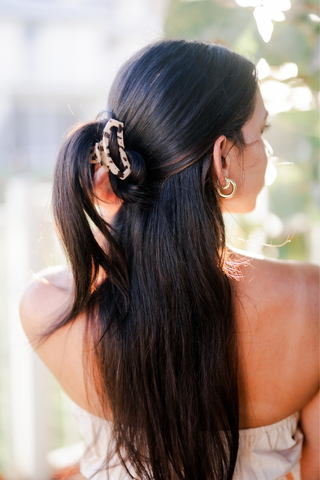 Woman wearing TELETIES open hair clip in tortoise pattern with long dark hair and gold earrings