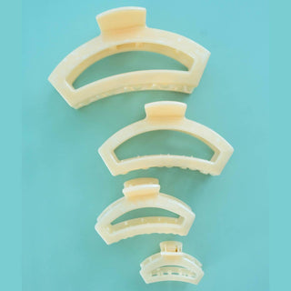 Four translucent curved hair clips in decreasing sizes arranged vertically on turquoise background