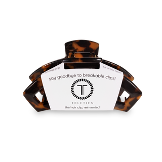 Tortoiseshell hair clip with white product label against black background showing TELETIES branding