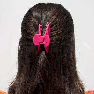 Woman wearing bright pink TELETIES open hair clip in brunette hair against white background.