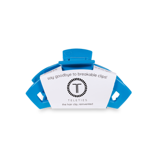 Blue spiral hair clip with white product label showing TELETIES branding and marketing text