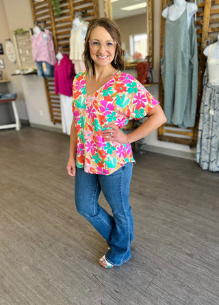 Woman wearing colorful floral v-neck top with jeans in clothing boutique store setting