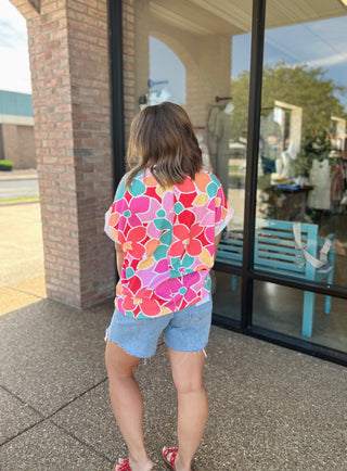 Woman wearing Haptics Paradise Floral Top with denim shorts, shown from behind outdoors.