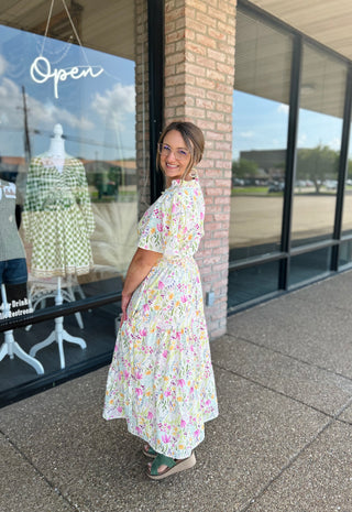 Woman wearing floral midi dress with short sleeves standing outside boutique storefront
