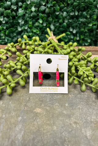 Pink and gold hoop earrings on packaging card displayed with green foliage background