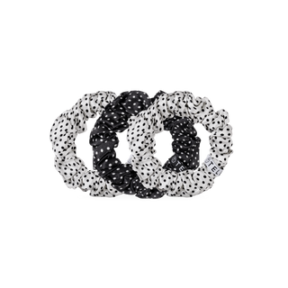 Three TELETIES polka dot silk scrunchies arranged overlapping on a black background.