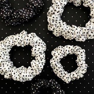 TELETIES polka dot silk scrunchies arranged on a black dotted background, showcasing classic spotted pattern design.